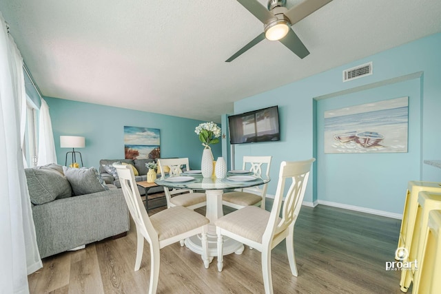 dining room featuring ceiling fan, hardwood / wood-style floors, and a textured ceiling