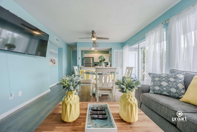 living room featuring ceiling fan, hardwood / wood-style flooring, and a textured ceiling