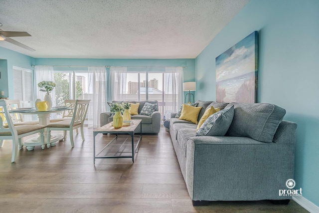 living room featuring ceiling fan, hardwood / wood-style floors, and a textured ceiling