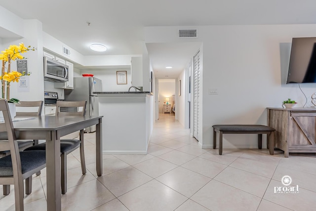 kitchen with appliances with stainless steel finishes, light tile patterned floors, and kitchen peninsula