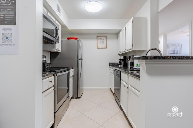 kitchen featuring light tile patterned flooring, appliances with stainless steel finishes, dark stone counters, and white cabinets