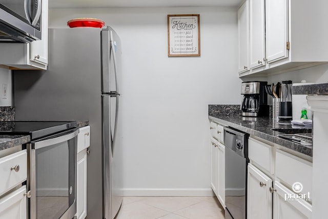 kitchen with light tile patterned flooring, stainless steel appliances, dark stone countertops, and white cabinets