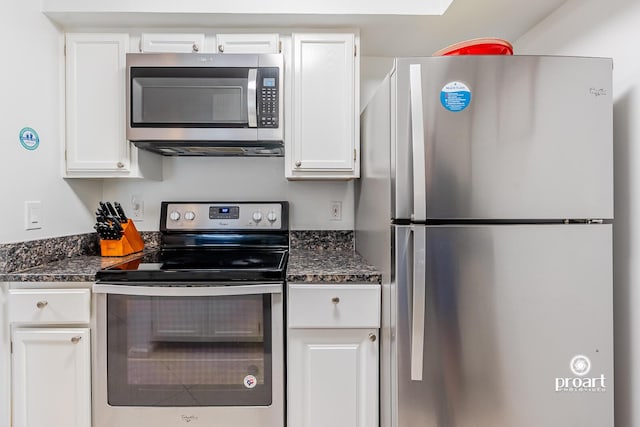 kitchen with stainless steel appliances, dark stone countertops, and white cabinets