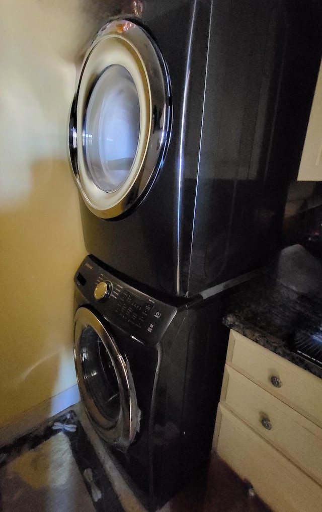 laundry area with cabinets and stacked washing maching and dryer