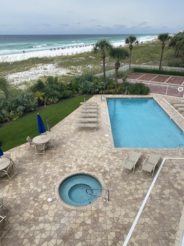 view of pool featuring a view of the beach, a water view, a patio area, and a community hot tub