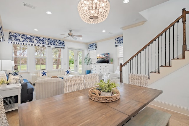 dining area with french doors, ornamental molding, and ceiling fan with notable chandelier