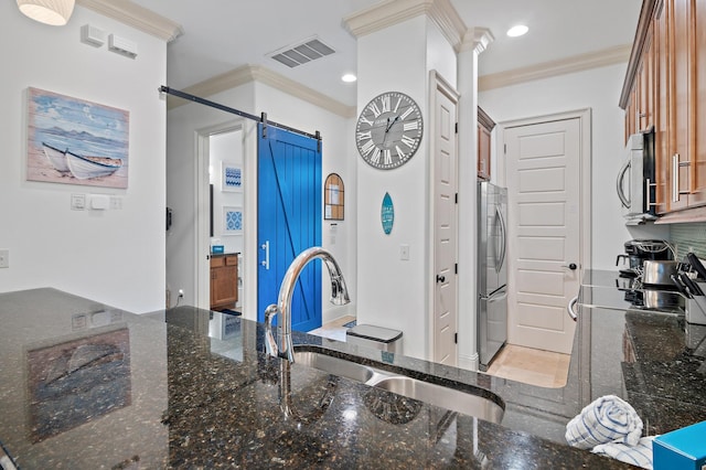 kitchen featuring dark stone countertops, sink, stainless steel appliances, and a barn door