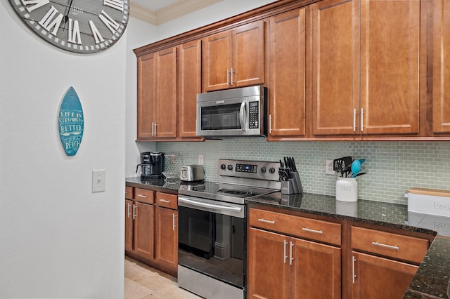 kitchen featuring dark stone countertops, decorative backsplash, ornamental molding, light tile patterned floors, and stainless steel appliances