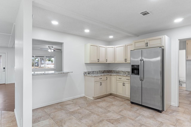 kitchen featuring ceiling fan, cream cabinets, light stone countertops, a textured ceiling, and stainless steel fridge with ice dispenser