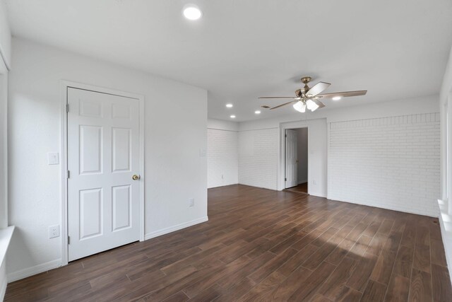 spare room featuring brick wall, dark hardwood / wood-style floors, and ceiling fan