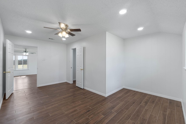 empty room featuring ceiling fan, dark hardwood / wood-style flooring, vaulted ceiling, and a textured ceiling