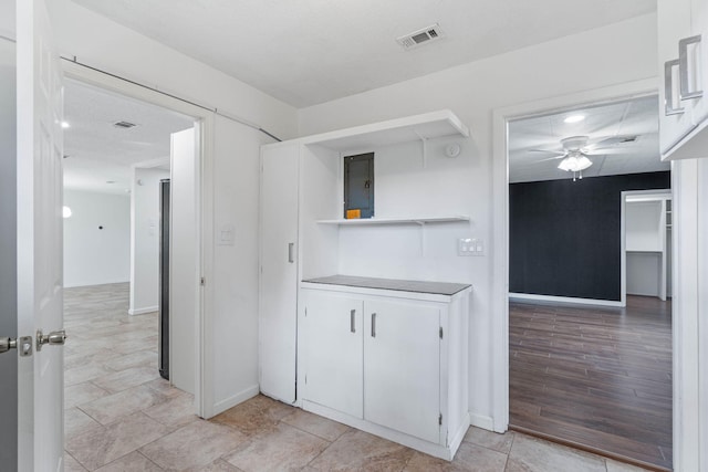 kitchen with white cabinetry, electric panel, and ceiling fan