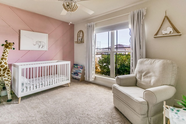 bedroom with a crib, wooden walls, ceiling fan, and carpet