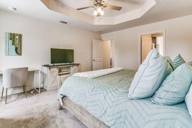 carpeted bedroom with a tray ceiling and ceiling fan