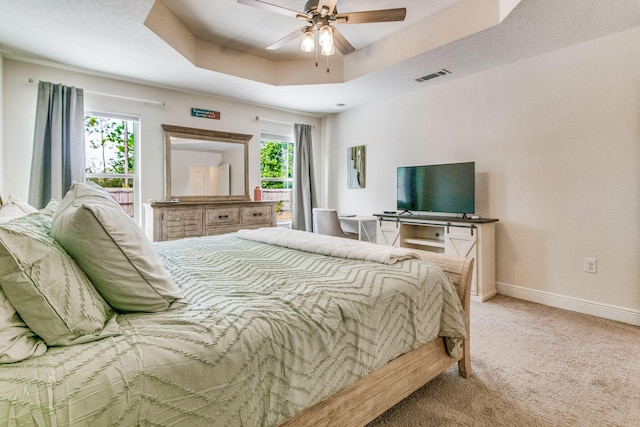 bedroom featuring ceiling fan, a raised ceiling, and carpet