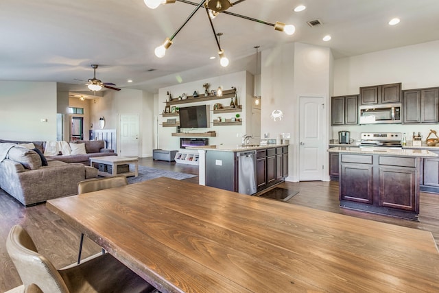 dining space with ceiling fan, dark hardwood / wood-style flooring, sink, and a towering ceiling