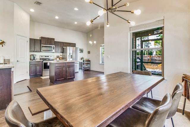 dining space featuring a high ceiling, dark hardwood / wood-style floors, and a notable chandelier