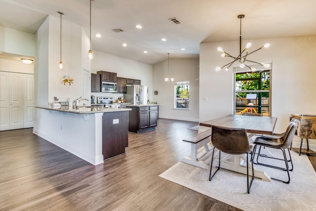 kitchen with dark brown cabinetry, decorative light fixtures, a chandelier, kitchen peninsula, and stainless steel appliances