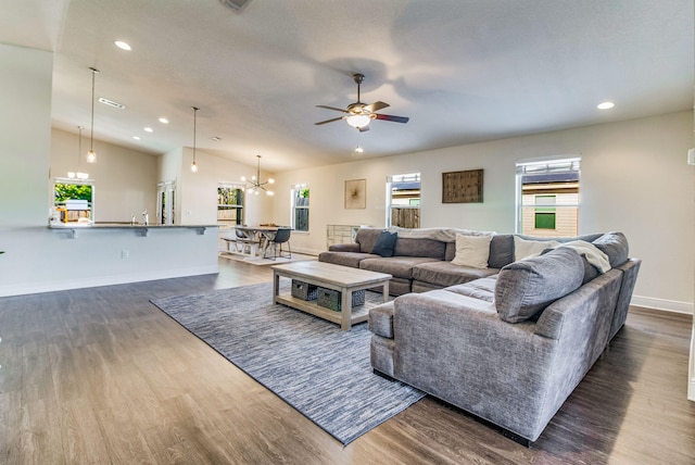 living room featuring lofted ceiling, ceiling fan with notable chandelier, and dark hardwood / wood-style floors