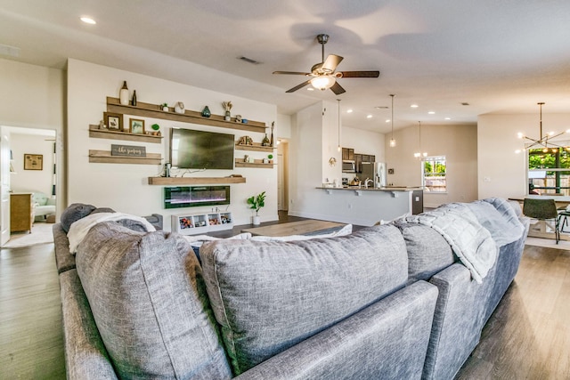 living room featuring dark wood-type flooring and ceiling fan with notable chandelier