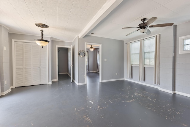 spare room featuring concrete floors, baseboards, a ceiling fan, and ornamental molding