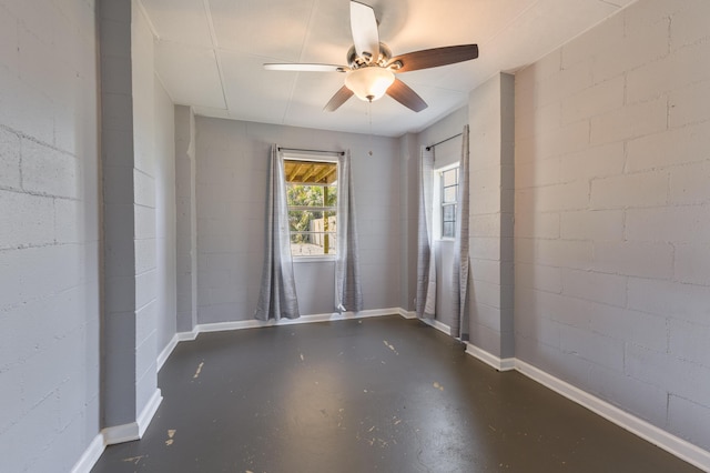 empty room featuring ceiling fan, concrete block wall, and finished concrete floors