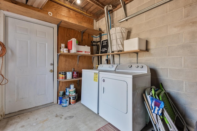 clothes washing area featuring concrete block wall, laundry area, and washer and dryer