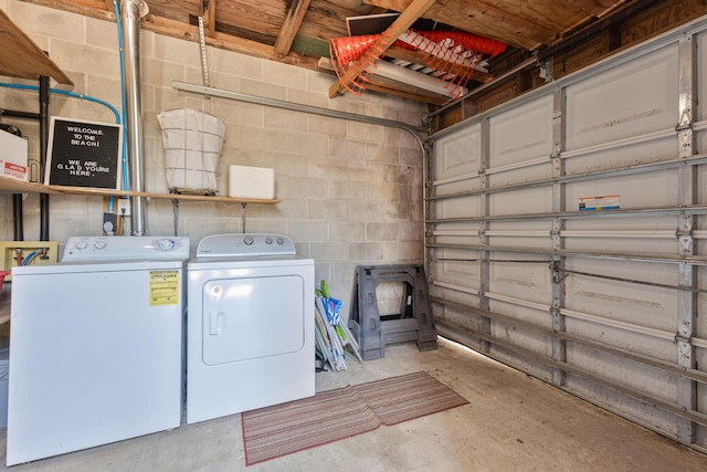 washroom with a garage, laundry area, independent washer and dryer, and concrete block wall