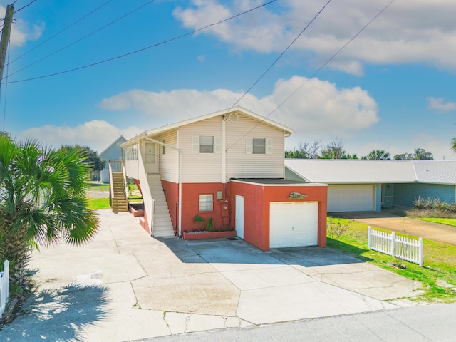 view of front of home with stairs, fence, and concrete driveway