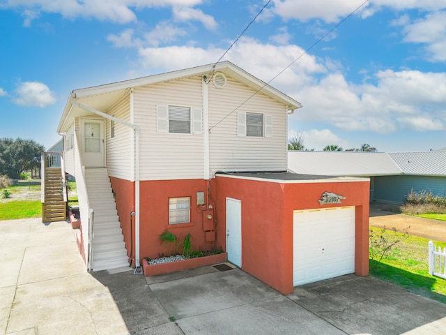 view of front facade with an attached garage, stairway, concrete driveway, and stucco siding