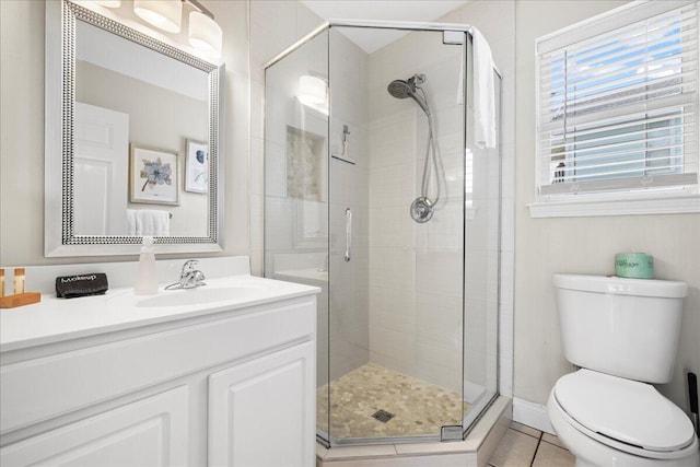 bathroom featuring tile patterned flooring, vanity, a shower with shower door, and toilet