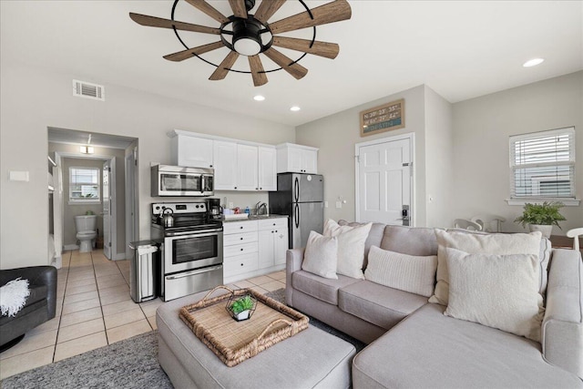 living room featuring light tile patterned floors, sink, and ceiling fan