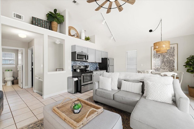 living room with light tile patterned floors, ceiling fan, and a high ceiling