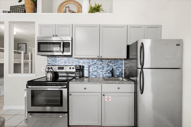 kitchen featuring light tile patterned flooring, sink, white cabinetry, tasteful backsplash, and stainless steel appliances