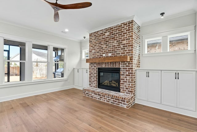 unfurnished living room with a brick fireplace, crown molding, and light hardwood / wood-style floors