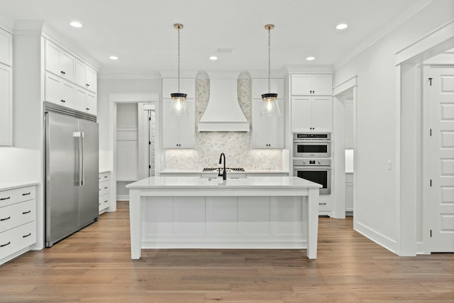 kitchen featuring crown molding, stainless steel appliances, an island with sink, decorative light fixtures, and custom exhaust hood