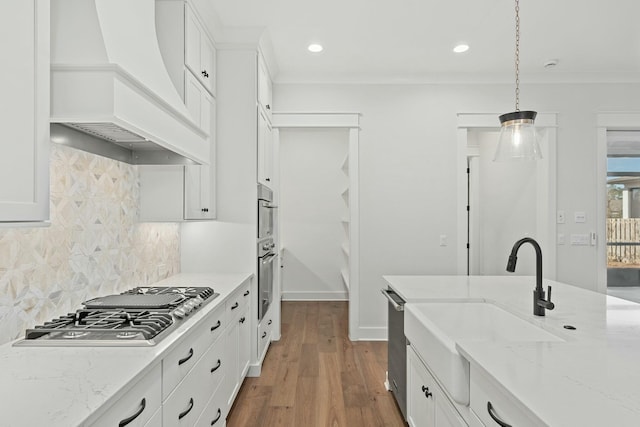 kitchen featuring light stone counters, white cabinetry, hanging light fixtures, custom range hood, and stainless steel appliances