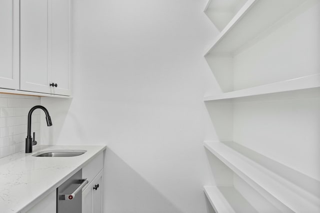 clothes washing area featuring cabinets and sink