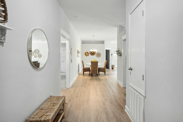 hallway with a notable chandelier and light hardwood / wood-style floors