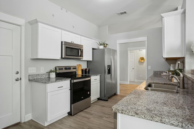 kitchen featuring white cabinetry, stainless steel appliances, sink, and light hardwood / wood-style flooring