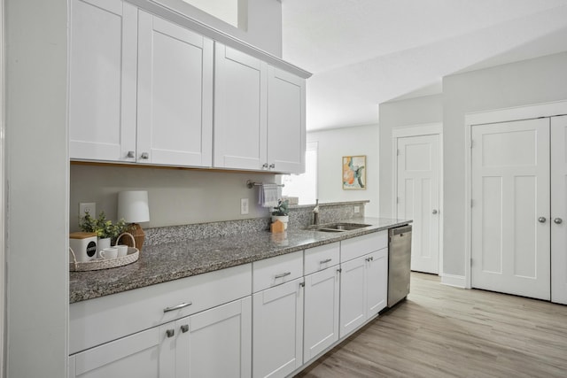 kitchen with dishwasher, sink, dark stone countertops, and white cabinets