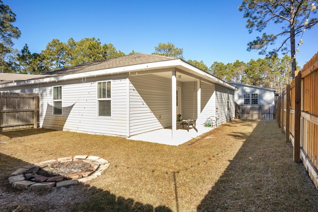 back of house featuring an outdoor fire pit, a yard, and a patio