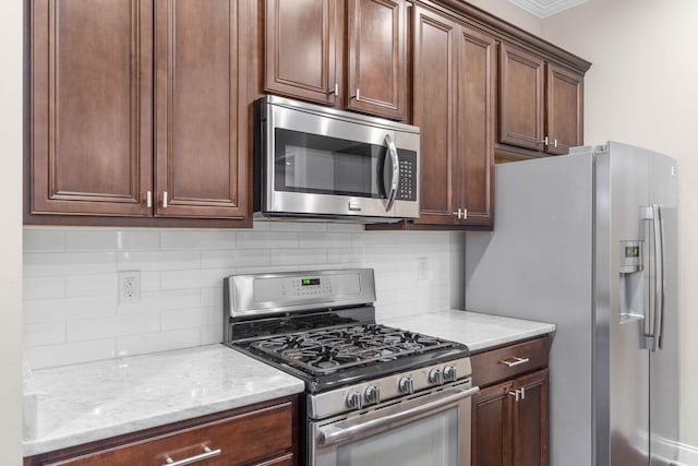 kitchen with tasteful backsplash, light stone countertops, ornamental molding, and stainless steel appliances