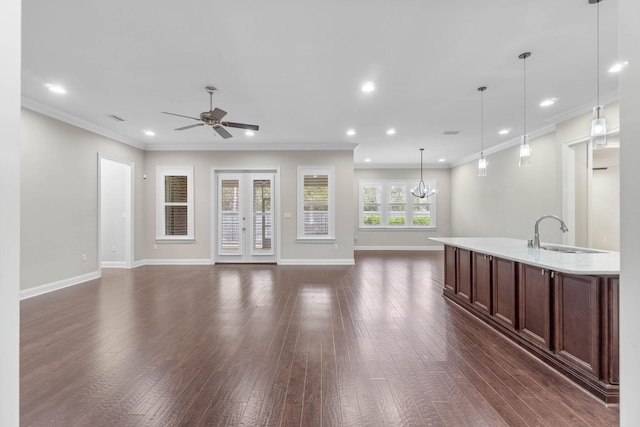 unfurnished living room with sink, crown molding, dark hardwood / wood-style flooring, ceiling fan with notable chandelier, and french doors