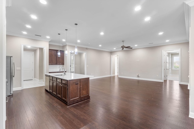 kitchen featuring pendant lighting, sink, ceiling fan, stainless steel appliances, and a center island with sink