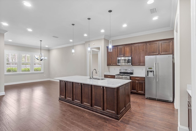 kitchen with sink, appliances with stainless steel finishes, hanging light fixtures, dark brown cabinetry, and a center island with sink