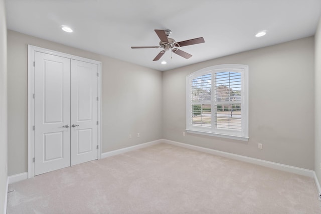 unfurnished bedroom with light carpet, a closet, and ceiling fan