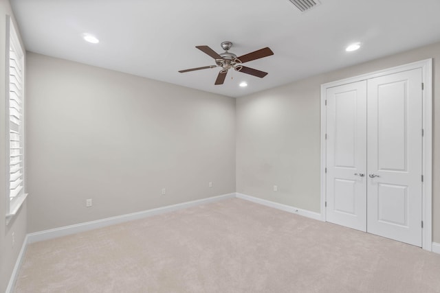 unfurnished bedroom featuring light colored carpet, ceiling fan, and a closet