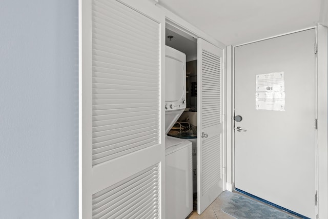 clothes washing area featuring light tile patterned flooring and stacked washer / dryer