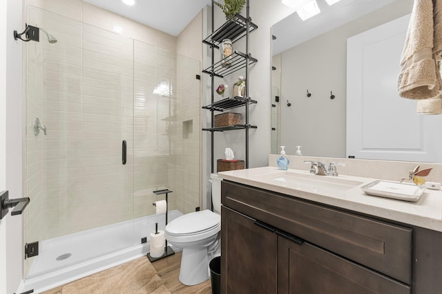 bathroom featuring hardwood / wood-style flooring, vanity, a shower with shower door, and toilet